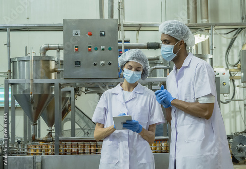 Two professional inspector sterile workwear use digital tablet monitor automated production line ensure efficiency food safety quality standard within modern industrial manufactur factory environment.