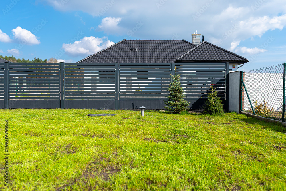 Obraz premium Modern house with green lawn and secure fence