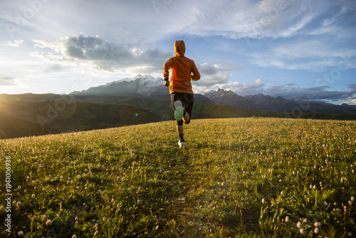 Trail runner running on the high altitude grassland mountain top trail