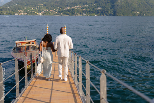 Romantic Lake Cruise Moment - Couple Walking Toward Boat on Waterfront Promenade