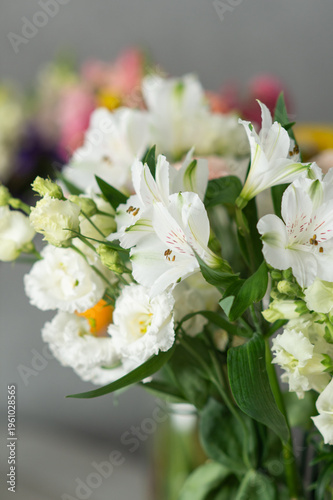 Vibrant bouquet of white alstroemeria and lisianthus flowers with green leaves in floral arrangement