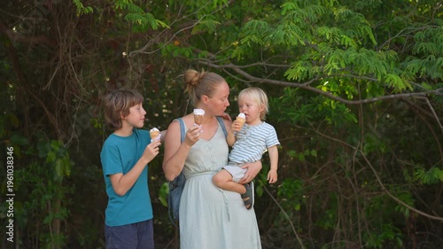 Young mom spending quality time with her two sons in a lush green park, enjoying nature, laughter, and joyful family bonding moments outdoors.