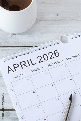 April 2026 calendar with coffee cup of wooden background.
