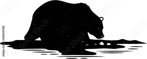 Silhouette of a bear drinking from a body of water with a mountainous horizon