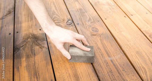 Quadro em tela Hand smooths wooden deck with a gritty scrubbing block