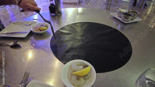 Close-up view of chef placing vegetables on hot stone plate for interactive cooking in restaurant. Aruba.