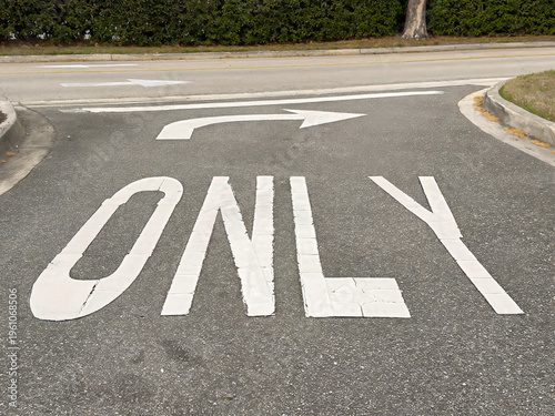 White pavement marking for a mandatory right turn on exit lane between two concrete curbs in front of a hospital (off camera), for motifs of traffic flow and safety