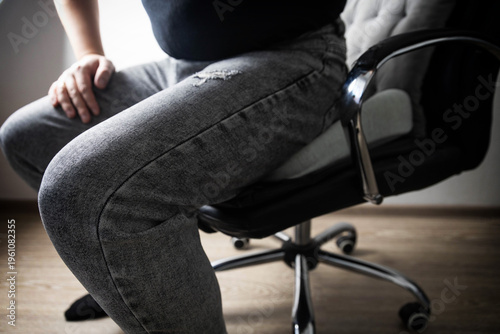 Man sits on orthopedic cushion for back pain relief, posture correction, spinal health. Device for disc herniation, osteochondrosis, sacral pain.