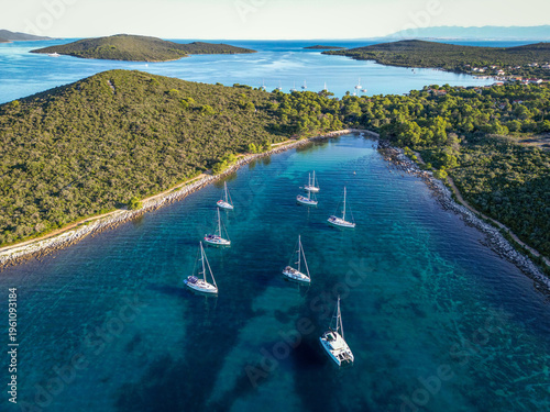 Photos Aerial drone view of flotilla of sailboats and catamaran anchored in sheltered c