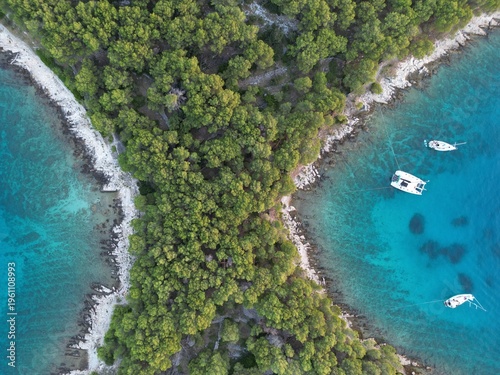 Bild auf Leinwand Aerial top-down view of narrow forested isthmus between two turquoise bays with