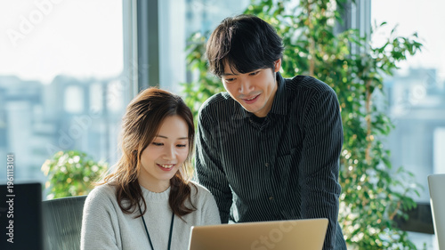 ノートパソコンを見ながら話し合う日本人男女のビジネスチーム（協働・コミュニケーション）