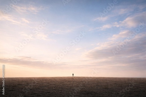 Lone Silhouette of a Person Standing on a Vast Horizon Under a Soft Pastel Sunset Sky