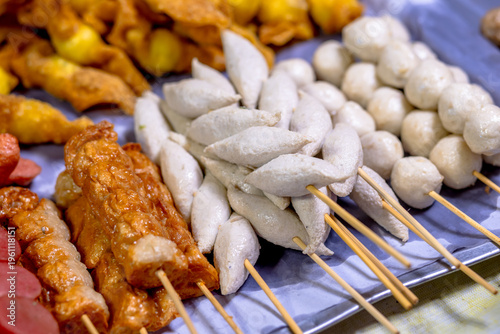 Meatballs on a stick, Assorted street food skewers including sausages, fish balls, and crab sticks displayed at a market stall. Grilled meatballs, Fried meatballs, ready to eat and visually appealing