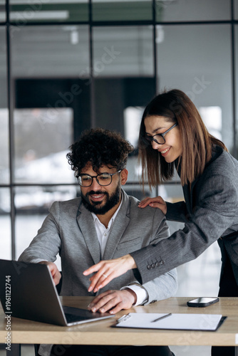 Two business people working at the office and looking into laptop