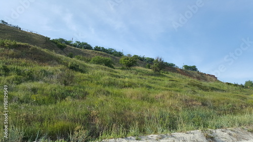 Fotografie View from beach to steep grassy берег with natural landscape