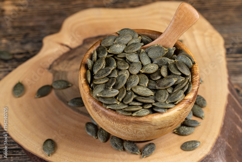 Foto peeled large dried pumpkin seeds are lying on a wooden walnut board and in woode