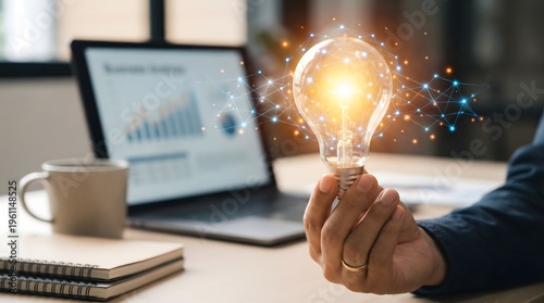 Hand Holding Glowing Lightbulb with Business Analytics in Background