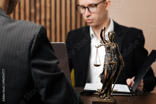 Lawyer consulting with client at office desk, discussing legal matters. Concept of justice and legal services.
