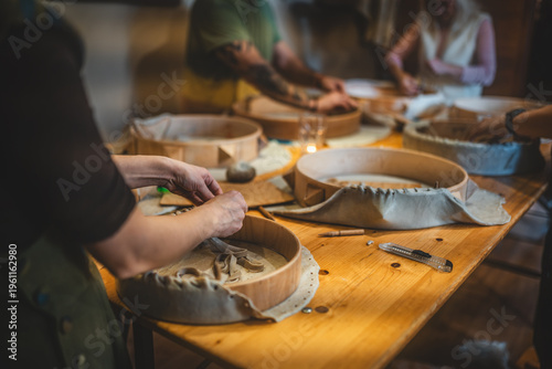Group of people crafting traditional shamanic frame drums at a creative workshop.
