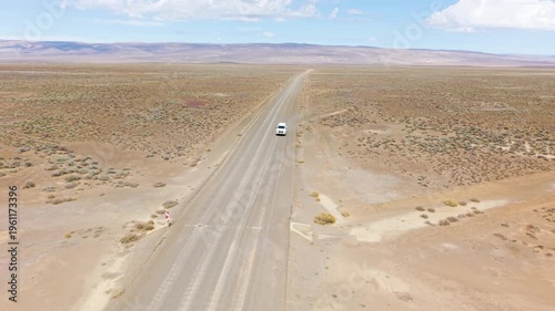 Aerial of car driving through arid desert landscape