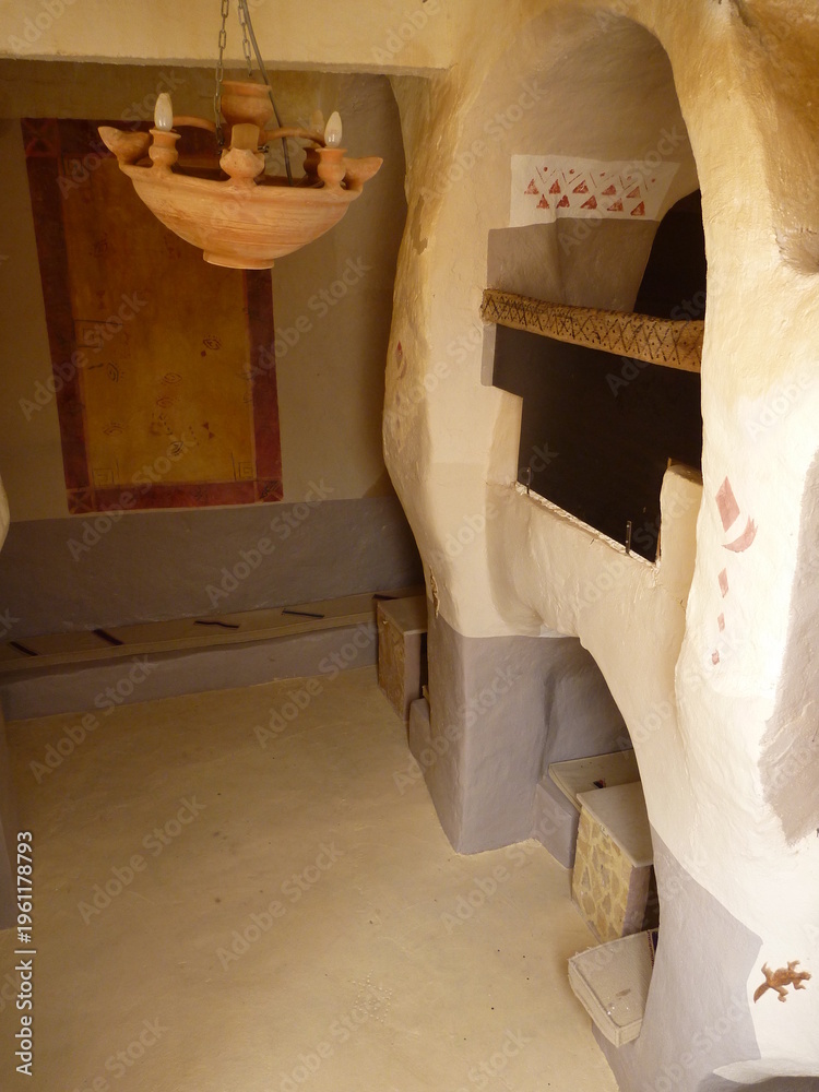 Naklejka premium Unique cave dwelling interior with rustic terracotta chandelier and built-in oven