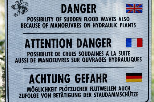 Multilingual Danger Warning Sign Sudden Flood Waves Hydraulic Plants English French German Flags Safety River Dam Water Management Hydroelectric Power Station Environment Industrial Hazard Caution Act