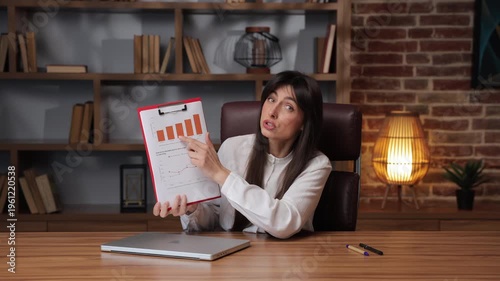 Caucasian business woman explains market trends using charts in an office setting.