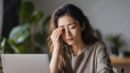 Young Woman Experiencing Headache and Stress While Working on Laptop at Home Office