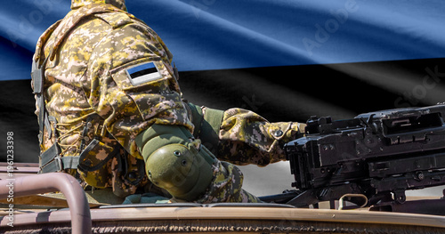 Estonia flag with soldier at machine gun turret in front of it. Closeup side view.