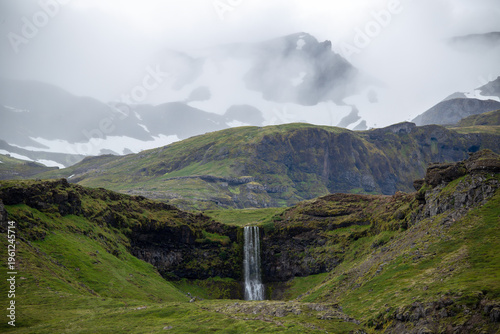Waterfall from snow melt in the green mountains of Iceland