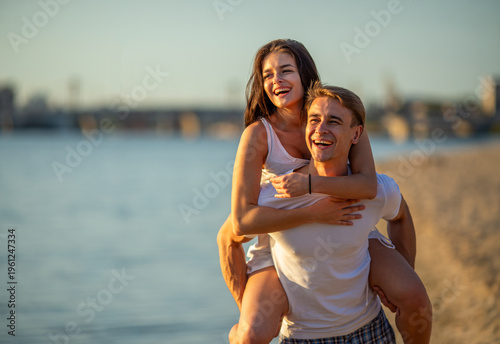 Foto Happy couple enjoying piggyback ride on beach.