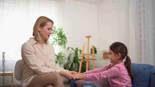 Psychologist holding hands with a young girl during therapy session