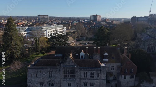Maidstone town and historic Archbishop's Palace early in the morning. Aerial rising view of business town skyline on a sunny Sunday. Public park and historic landmark by the river.