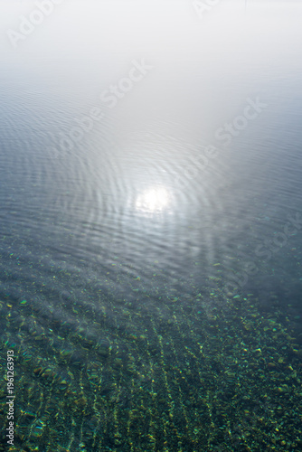 Die Sonne spiegelt sich auf einer ruhigen Wasseroberfläche