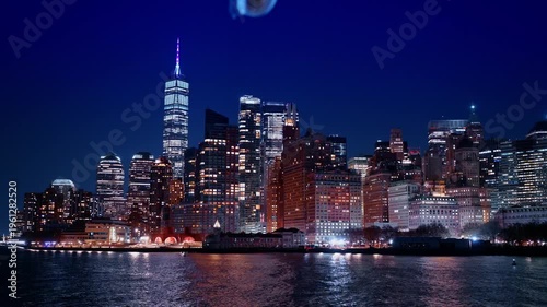 Cluster of modern high-rise buildings with bright illumination at night. Admiring gorgeous city from the boat travel.
