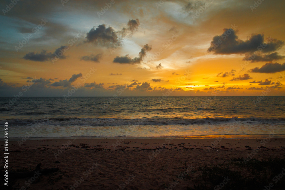 Obraz premium Golden ocean sunset with soft waves and cloudy sky