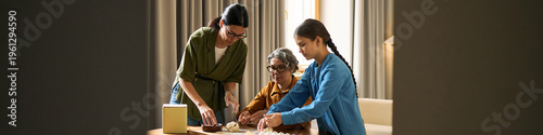 Bilde på lerret Wide header of two women and girl preparing pastry dough together at home, showing family bonding and intergenerational learning