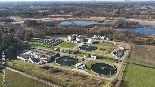 Diepenbeek, Belgium. Aerial drone footage of wastewater treatment facility with circular basins and solar panels in rural landscape