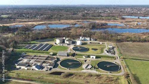 Diepenbeek, Belgium. Aerial drone footage of wastewater treatment facility with circular basins and solar panels in rural landscape