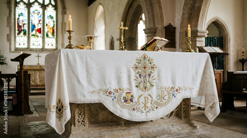 Church altar with embroidered white cloth and lit candles. Sacred interior of a cathedral with a golden cross and chalice. Christian worship and liturgy concept