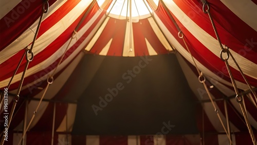 Interior view of a red and white striped circus tent with ropes and overhead lighting, dramatic big top carnival atmosphere.