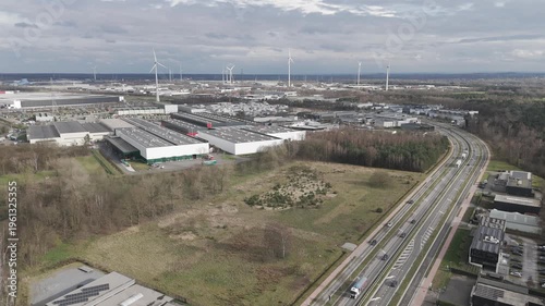 Genk, Belgium. Aerial drone glide over industrial zone with highway traffic and wind turbines