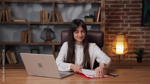 Business woman files paperwork in modern office setting during daylight hours.