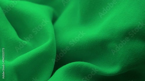 A green fabric with elegant wavy folds. Close up.