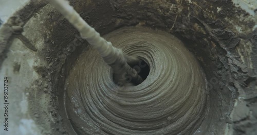 A man kneads tile mortar in a bucket with a paddle mixing drill. Mixing tile mortar for laying ceramic tiles or porcelain tiles. Close-up