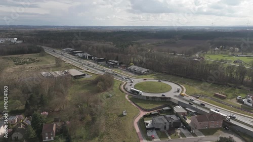 Genk, Belgium. Aerial drone footage of busy roundabout with trucks and suburban-industrial surroundings