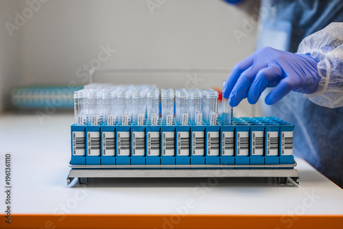 Closeup Hand Selecting Labeled Tube From Rack, Focused View On Careful Grip, Barcode Labels, Gloved Fingers,