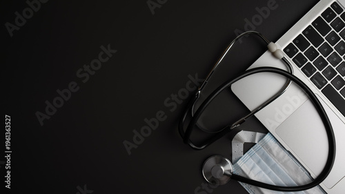 Digital health and telemedicine concept. Stethoscope, laptop and protective face mask on dark desk background. Online medical consultation.