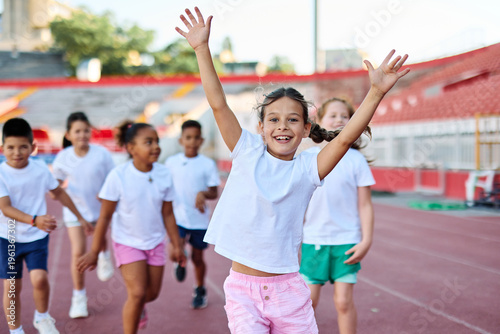 Young children having athletic exercise class running on the track, healthy lifestyle and children sport education concepts, finish line winner celebration, victory and success