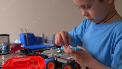 Focused Child Changing Batteries in Electronic Toy, Boy Replacing AA Power Cell at Desk, Hands-on Maintenance and Practical Skills for Kids
